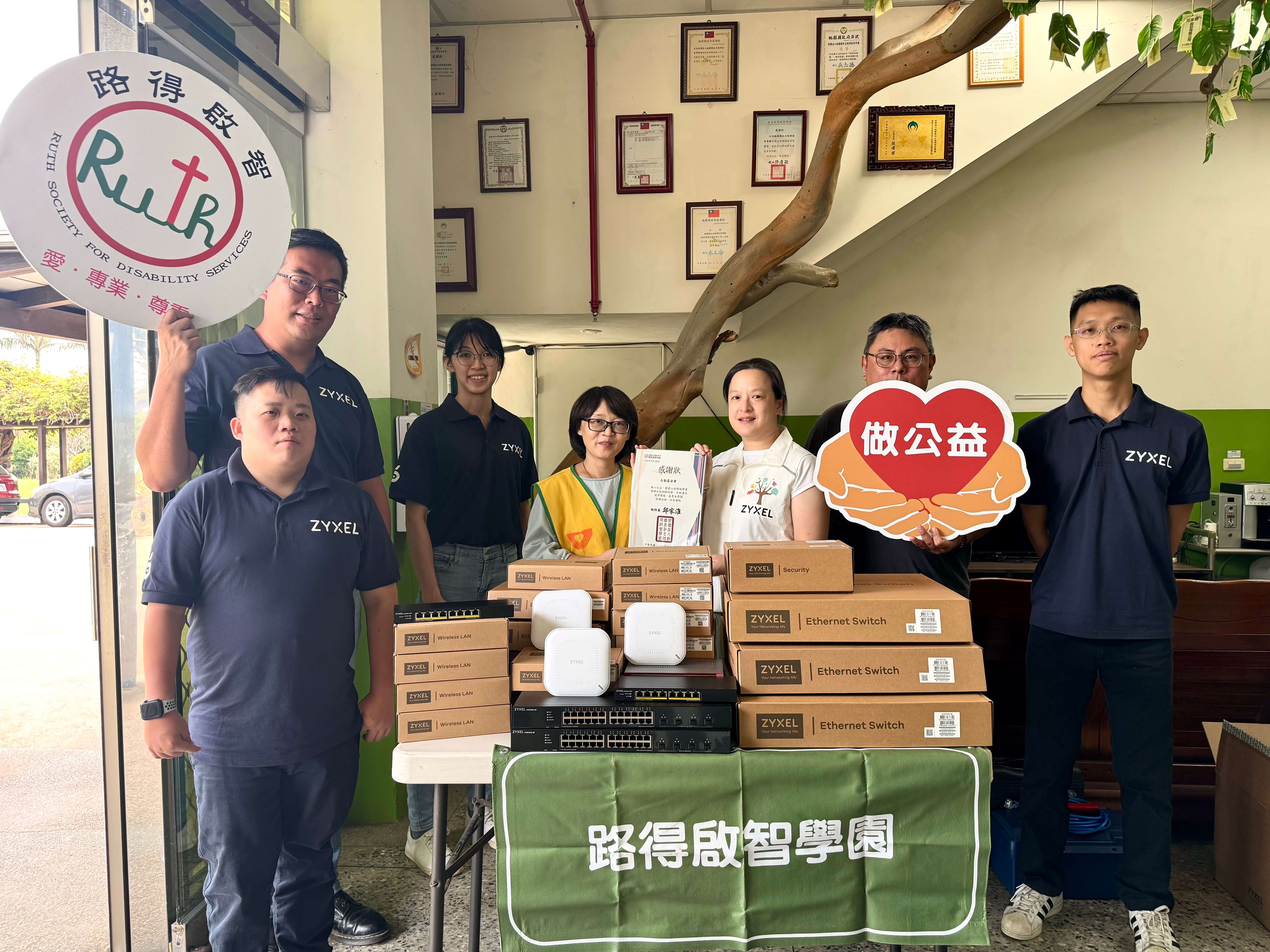 Zyxel Networks volunteers gather around a table with boxes, supporting the Ruth Society for Disability Services.