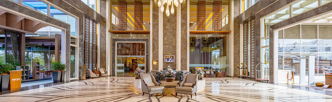 Case study: A modern Indian hotel lobby with seating areas, a marble reception desk, high ceilings, and hanging lights 