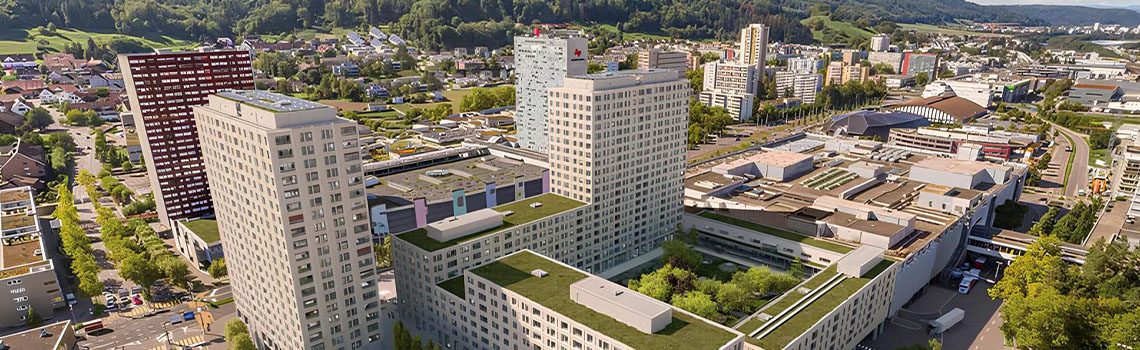 Aerial view of a modern multi-building apartment complex in Switzerland with green rooftop gardens in an urban landscape.
